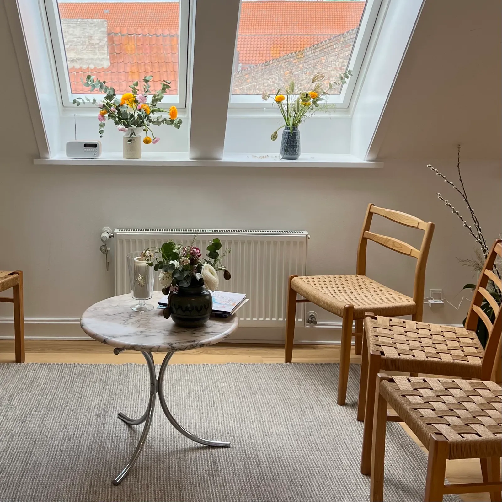 Venteområde hos VenligtSind med blomster, dagslys og danske designstole